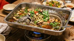 Đĩa cá tầm hấp xì dầu nguyên con thơm ngon xèo xèo trên bếp cồn với nấm hương và rau gia vị