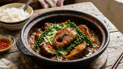 Nồi đất đựng món cá tầm kho tiêu óng ánh với nước xốt sánh kẹo và những chùm hạt tiêu xanh tươi mát hấp dẫn